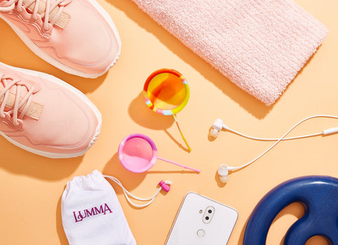Disco coletor menstrual se colocando lado a lado de itens de atividades físicas como toalha, anilha e tênis de corrida